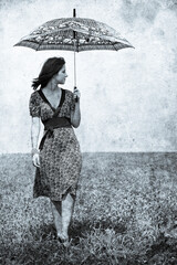 Girl with umbrella on field. Photo in old image style.