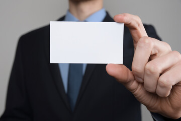 Businessman ,Business Man's hand hold showing business card - close up shot on grey background. Show a blank piece of paper. Paper visit card