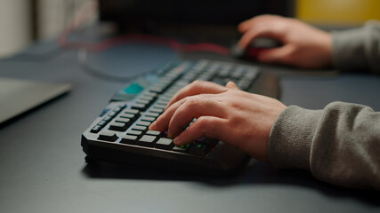 Close-up on hands of pro cyber man playing video game using RGB keyboard. Virtual championship in cyberspace, esports player performing on powerful computer during online esports gaming tournament © DC Studio
