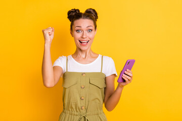 Photo of excited crazy lady raise fist hold telephone open mouth wear green overall isolated yellow background