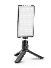 Small size led lamp for photo and video production stands on a tripod.