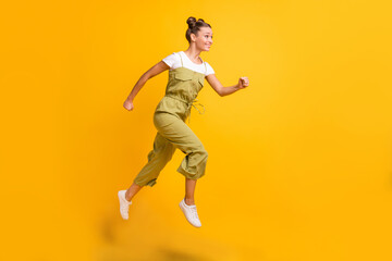 Fototapeta na wymiar Full length body size view of pretty cheerful active girl jumping running motivation isolated over bright yellow color background