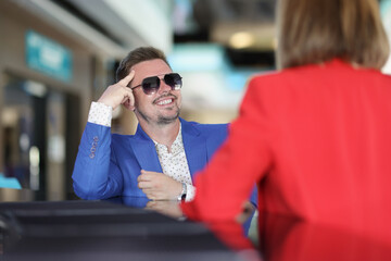 Smiling stylish man in sunglasses sitting at bar counter with woman