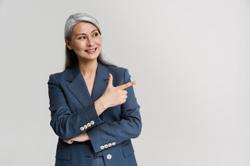 Asian mature woman smiling while pointing finger aside