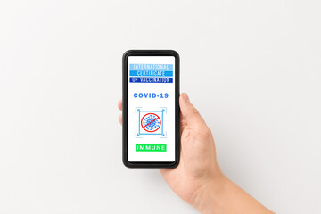 technology and health care concept - close up of hand holding and showing smartphone with international certificate of vaccination on screen over grey background