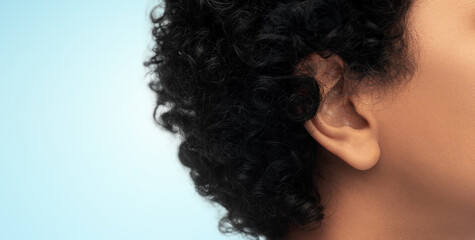 hearing, health and beauty concept - close up of african american woman's ear over blue background