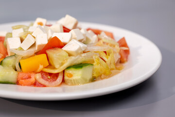 Greek salad in a white plate on a gray background