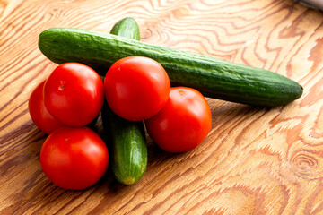 two cucumbers and four tomatoes on a wooden background
