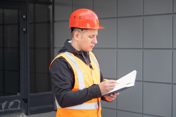 construction engineer in white helmet and workwear reading design drawing plan on construction area. architecture construction concept. Industrial safety