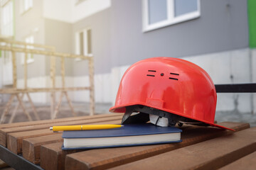 protective helmet and notebook on the background of the construction site