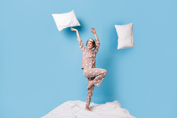 Full size photo of young lovely happy cheerful girl in pajamas with flying pillows around isolated...