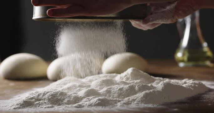 Chef prepares dough for traditional Italian pizza. Cooker sprinkles flour on dough in kitchen, 4k footage