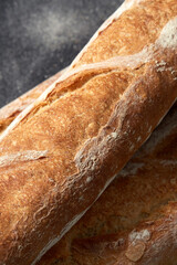 food, baking and cooking concept - close up of baguette bread on table over dark background