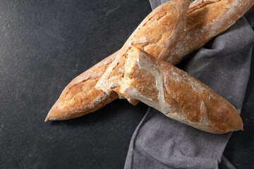 food, baking and cooking concept - close up of baguette bread on kitchen towel