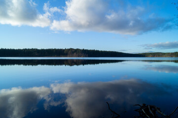 Northern boreal lake in forest with reflection trees in blue water