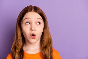 Photo of impressed nice foxy hair girl look empty space wear orange t-shirt isolated on purple color background