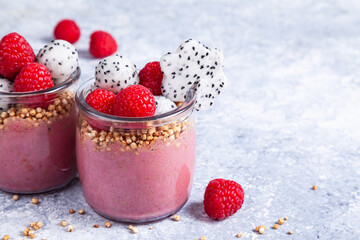 Smoothie with raspberries, banana, pitahaya, quinoa and almond milk in glass jars.