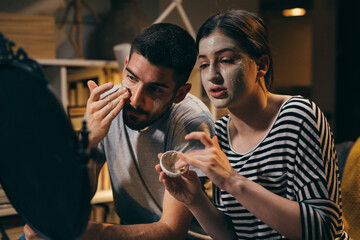 couple applying cosmetic clay face mask at home