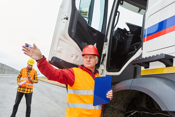 Bauleiter an LKW mit Checkliste gibt Richtung vor