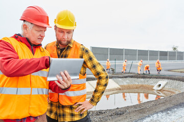 Obraz na płótnie Canvas Architekt und Vorarbeiter mit Tablet PC vor Baugrube