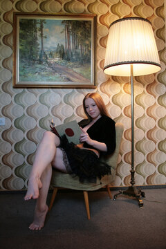 Eine Frau liest ein Buch in einem altmodischen Zimmer sitzend