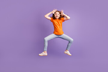 Fototapeta na wymiar Full body photo of funny ginger hair girl jump play wear t-shirt jeans isolated on purple background