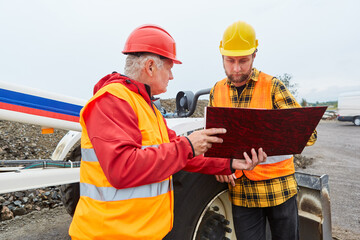 Architekt und Bauarbeiter mit Unterlagen auf Baustelle