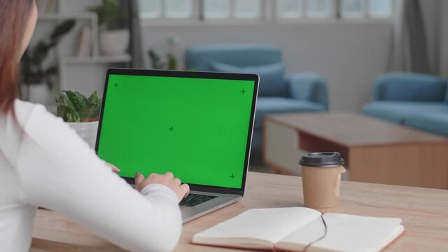 Girl Typing On Computer Keyboard Of A Laptop Computer With Green Screen Display At Home