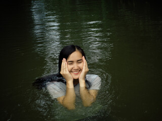 Beautiful woman wearing a white blouse A smiling face happily playing in the stream having fun on holiday.