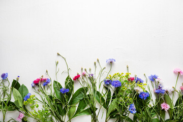 Overhead view of summer flowers on white surface
