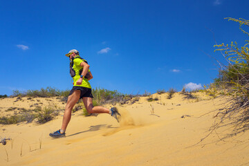 Athlete running off-road in the wild. A man in shorts and a T-shirt is running through the sandy wilderness