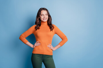 Portrait of intrerested inspired girl look empty space hands hips isolated on blue background