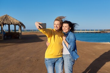 Two mature happy women taking selfie photo together using smartphone