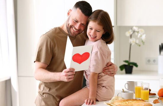 Cute girl daughter congratulating dad with Fathers day in morning at home