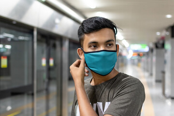 Portrait of handsome young man with a medical mask in casual style t-shirt standing, raised arms...