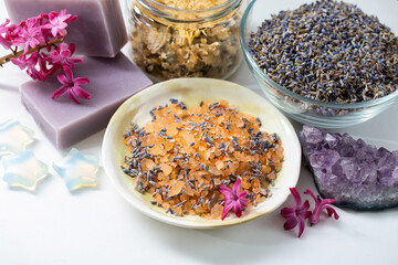 Organic aromatic sea salt, dried lavender and chrysanthemum in glass jars, amethyst crystals, handmade soap on a white background