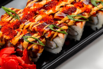 Asian rice and fresh fish rolls with hot sauce garnished with sliced onions and red fish roe. Stock image of exotic oriental food close-up