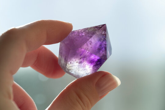 Amethyst crystal in hand. Purple translucent crystal close-up