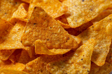 Mexican corn chips nachos triangular shape with cheese flavor. Quick salty snack shot close up