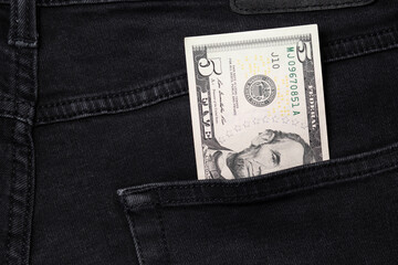  Five dollar bill sticking out of the pocket of black jeans