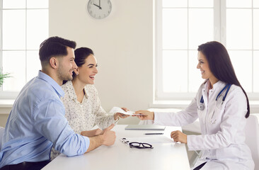 Consulting family doctor at clinic. Happy patients take therapy prescription that general...