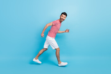 Fototapeta na wymiar Full size profile side photo of cheerful positive young man walk run empty space isolated on pastel blue color background