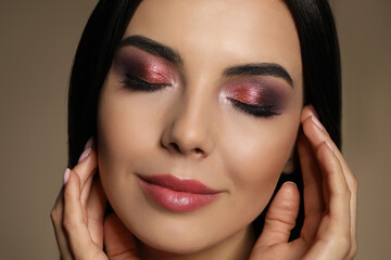 Fototapeta na wymiar Beautiful young woman with evening makeup on brown background, closeup. Eye shadow product