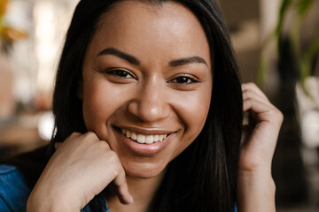 Black young woman smiling and looking at camera indoors