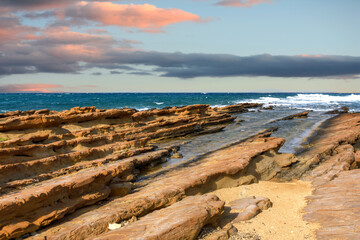 Sharp rocks, from sedimentary rocks in the stormy sea with the cloudy sky