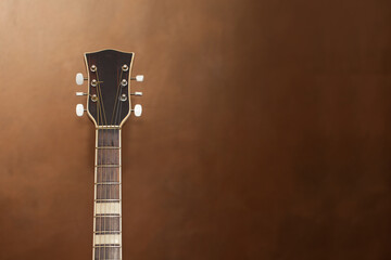 Fragment of a neck with the headstock of an acoustic guitar on a blurred background.