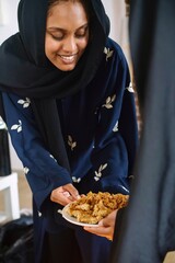 Muslim women wearing abayas gifting and sharing Arabic sweets during Ramadan