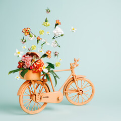 Retro orange bicycle with flowers flying out of basket against pastel green background. Creative...