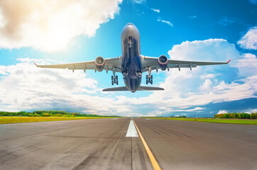 Rapidly plane taking off runway, airstrip with marking on blue sky with clouds background. Travel...