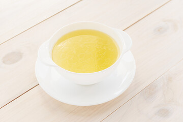 Bone broth in a bowl on a wooden table. Healthly food.